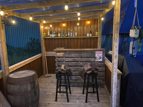 a wooden bar with two stools and a barrel at Horse Truck Tiny Home in Swords