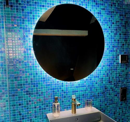 a blue tiled bathroom with a sink and a mirror at Vintner Suites in Neustadt an der Weinstraße