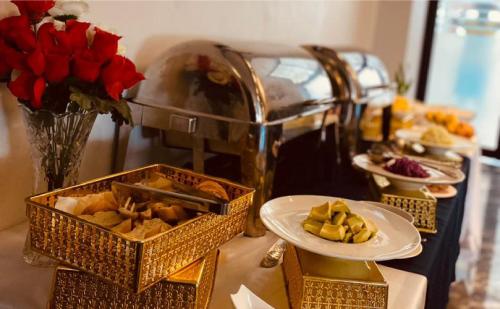 a table with plates of food and flowers and roses at Hôtel Vendôme Douala in Douala