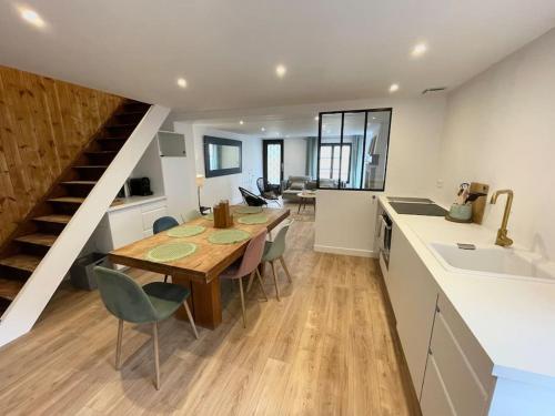 eine Küche und ein Esszimmer mit einem Tisch und einer Treppe in der Unterkunft Maison à Petit Fort Philippe .1mn de la plage in Gravelines