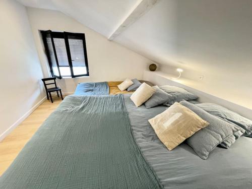 une chambre avec un grand lit avec des oreillers dessus dans l'établissement Maison à Petit Fort Philippe .1mn de la plage, à Gravelines