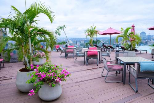 a patio with tables and chairs and palm trees and flowers at Exquisite 2BD at Skynest Residences with rooftop heated pool in Nairobi