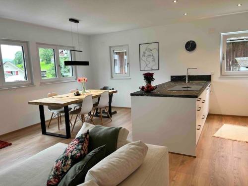 a kitchen and living room with a table and a couch at Ferienwohnung in Neubau in Schellenberg