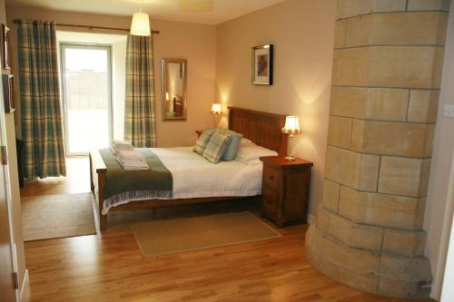 a bedroom with a bed and a stone wall at Abbey Garden at the Highland Club in Fort Augustus