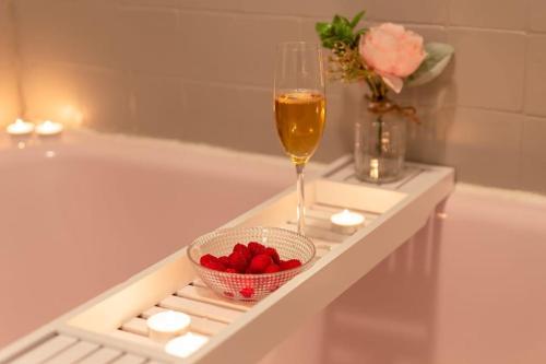 - un verre de vin et un bol de fraises dans la baignoire dans l'établissement Le Lumineux 50 m² Gare/château/wifi/Netflix, à Versailles