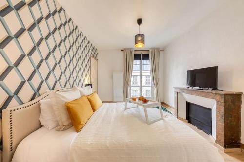 ein Schlafzimmer mit einem großen Bett und einem Kamin in der Unterkunft Le Lumineux 50 m² Gare/château/wifi/Netflix in Versailles