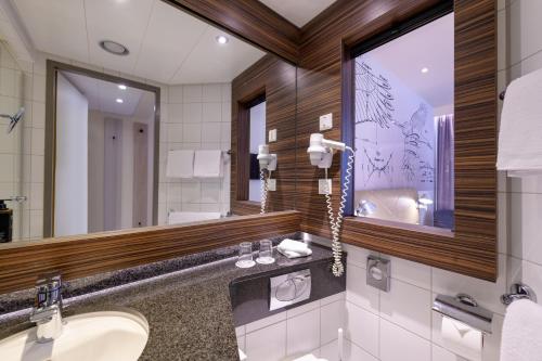 a bathroom with a sink and a mirror at Mercure Hotel Berlin City in Berlin