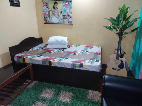 um quarto com uma cama com uma guitarra e uma planta em OYO Home Narayan Homestay & Adventures em Pelling