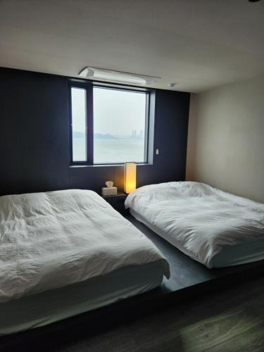 a bedroom with two beds and a window at Banwol Poolvilla in Busan