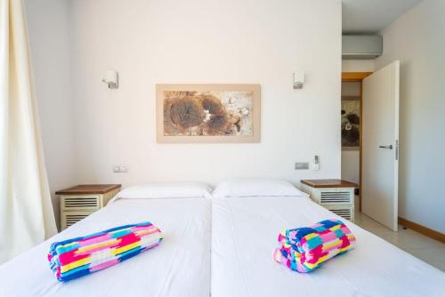 Una cama blanca con dos almohadas coloridas. en Villa Vista Golf Salobre - Maspalomas self-sufficient with pool heating, en Maspalomas