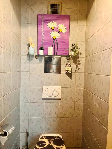 a bathroom with a painting of flowers on the wall at 10 min from U1 - Private room in shared apartment in Vienna