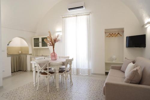 sala de estar blanca con mesa y sofá en Le Cementine - Apulian Rooms, en Fasano