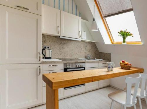 eine Küche mit weißen Schränken und einer Holzarbeitsplatte in der Unterkunft Wattnest - Ferienwohnung direkt in erster Meereslinie am Deich in Friedrichskoog