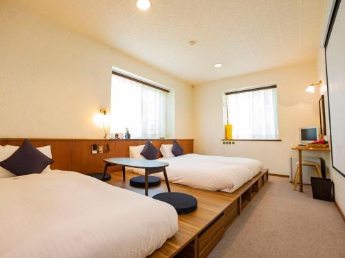 We Home Villa ～城ケ崎温泉～ في Futo: غرفة فندقية بسريرين وطاولة