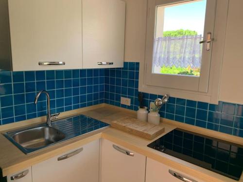 uma cozinha com um lavatório e uma parede de azulejos azuis em Villa Margiu em Villasimius