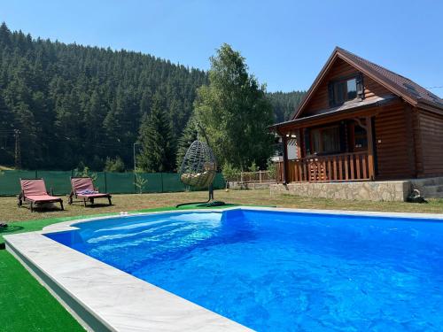 a large blue swimming pool in front of a house at Еднофамилна дървена къщичка in Beli Iskar