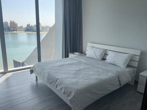 a bed in a room with a large window at Sama Chalet kuwait in Al Khīrān