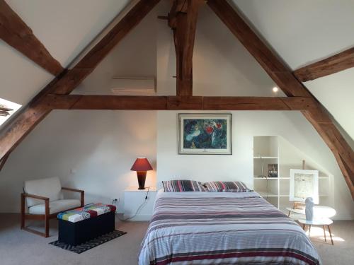 1 dormitorio en el ático con 1 cama y 1 silla en Gite PASSIFLORE, en Cour-Cheverny