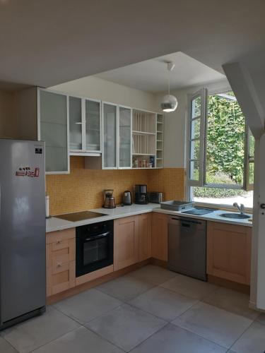a kitchen with wooden cabinets and a stainless steel refrigerator at Gite PASSIFLORE in Cour-Cheverny