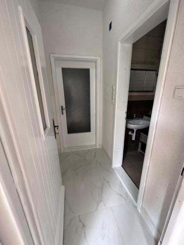 a white hallway with a sink and a mirror at Apartment Rea Ilidža 2 in Sarajevo