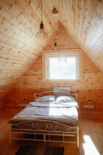a bed in a wooden room with a window at Domki Wielka Woda in Dywan