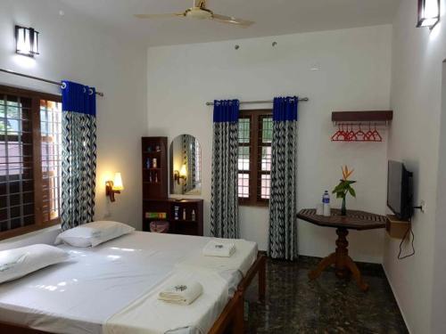 a bedroom with two beds and a table with a tv at Southcanal Holidays in Alleppey