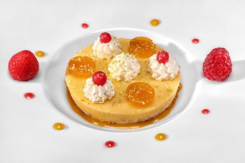 a dessert with oranges and whipped cream and raspberries at Hôtel & SPA Château de La Côte - Brantôme in Biras