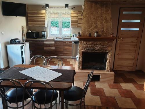 une cuisine avec une table à manger et une cheminée dans l'établissement Domek w Bieszczadach u Ani Apartament 3, à Uherce Mineralne