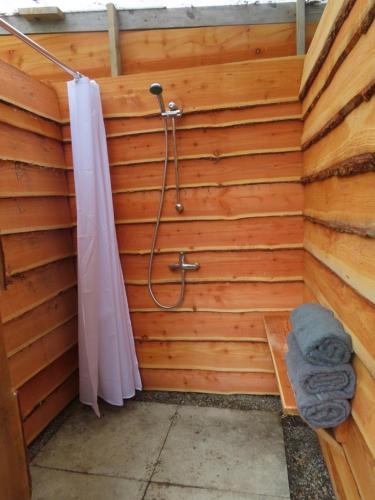 a shower in a wooden wall with a shower curtain at Dingly Dell 3 x bell tents in Cemmaes