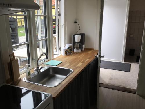 a kitchen counter with a sink and a window at Stubbekøbingrooms in Stubbekøbing