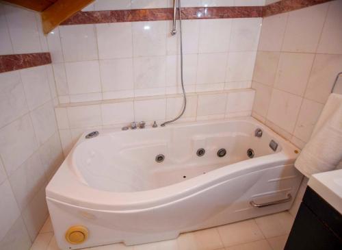 a white bath tub in a white tiled bathroom at Bourtzi View Villa in Nafplio