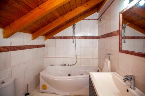 a white bathroom with a tub and a sink at Bourtzi View Villa in Nafplio