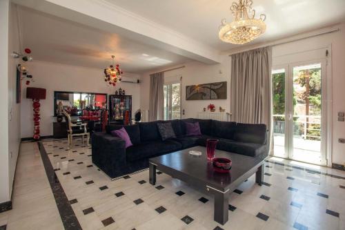 sala de estar con sofá negro y mesa en Unique, elegant Bourtzi View Villa en Nafplio