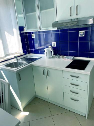 a kitchen with white cabinets and a sink and blue tiles at Apartments Ivandić in Tučepi