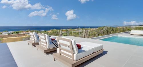 a row of chairs sitting on a patio next to a swimming pool at Villa Regatta in Hato