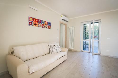 a white living room with a couch and a window at Appartamento nuovissimo con parcheggio gratuito in Massa