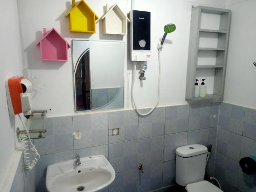 een badkamer met een wastafel, een toilet en een spiegel bij Tumombuvoi Homestay (Sidi place) in Tiga Papan