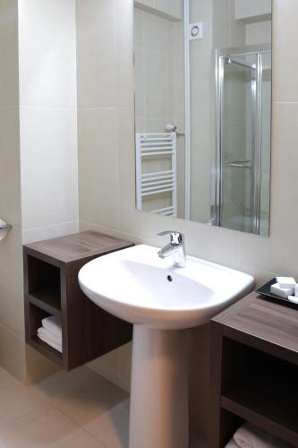 a bathroom with a white sink and a mirror at Hotel McPietroasa in Haleş