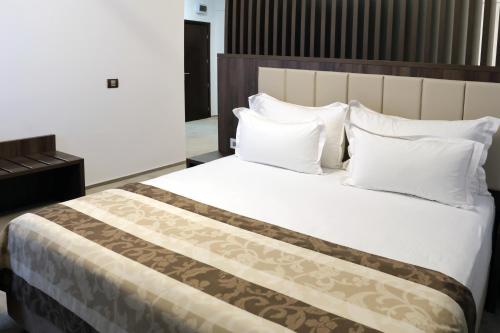 a bedroom with a large bed with white pillows at Hotel McPietroasa in Haleş