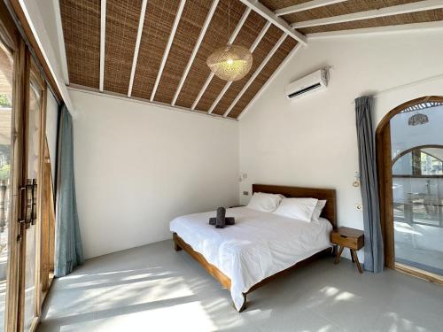 een slaapkamer met een bed en een groot raam bij Rumah Canaria Bungalow in Gili Trawangan