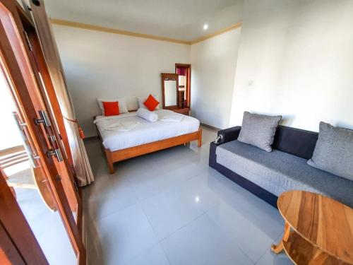 Zimmer mit einem Bett, einem Sofa und einem Tisch in der Unterkunft Batur Happy House in Kintamani