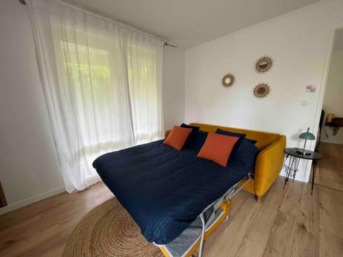 een slaapkamer met een bed met blauwe lakens en oranje kussens bij Hana Home T2 Spacieux avec jardin privatif in Montigny-le-Bretonneux