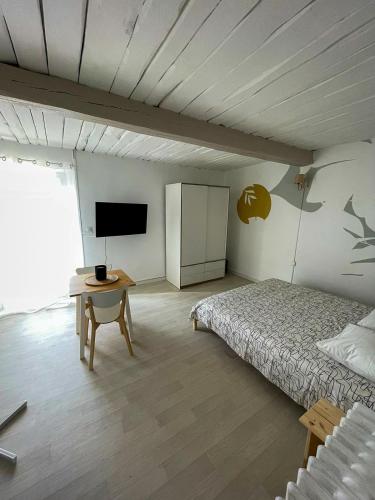 - une chambre avec un lit et une table avec une télévision dans l'établissement Grand Studio à 5mns de la Plage des Salins, à Hyères