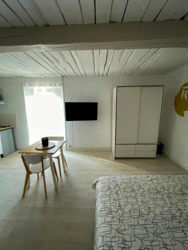 une chambre avec un lit, une table et une télévision dans l'établissement Grand Studio à 5mns de la Plage des Salins, à Hyères
