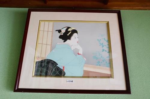 a framed picture of a woman sitting on a wall at まんのう清流庵 in Manno