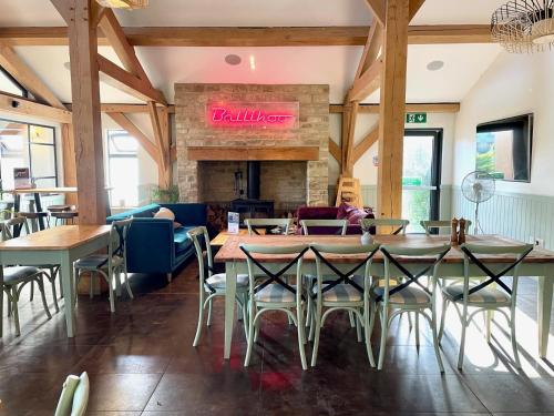 a restaurant with tables and chairs and a fireplace at Cosy Cotswold Lodge by Your Home Here - SUMMER SALE for 3 PLUS NIGHTS - ideal for families with log-burner, spa, private parking, EV recharging and heated swimming pools in Ashton Keynes