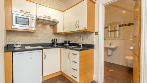 a small kitchen with a sink and a microwave at Teddington Lodge in Teddington