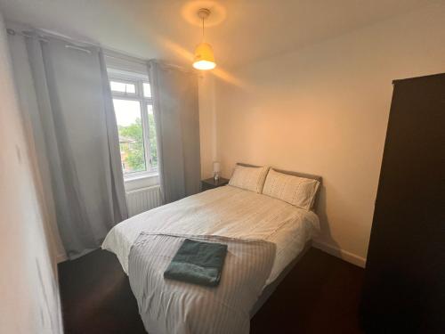 a small bedroom with a bed and a window at Neasden, Dollis Hill London Apartment in London