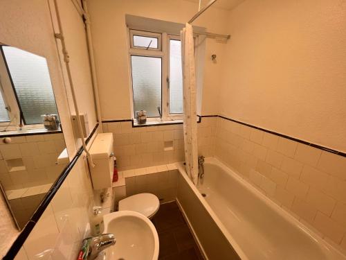 y baño con lavabo, aseo y bañera. en Neasden, Dollis Hill London Apartment, en Londres