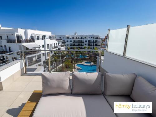 un sofá en el balcón de un apartamento en Homity Exclusive Playa Granada Beach & Golf - Aguacate Beach, en Motril